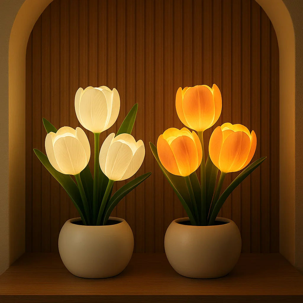 Two Lumiere Blossom LED decorative lamps, one with three glowing white tulips and another with three glowing orange tulips, displayed side by side on a wooden shelf in an arched alcove.